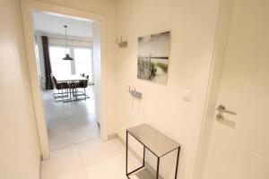 a white bathroom with a bench and a table at Seeblick 5 - Luxus am Hafen in Norddeich