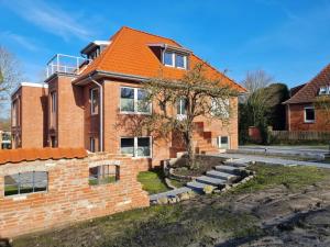 ein Backsteinhaus mit orangefarbenem Dach in der Unterkunft Die Zimmerei 2 - Luxus in Greetsieler Toplage in Krummhörn