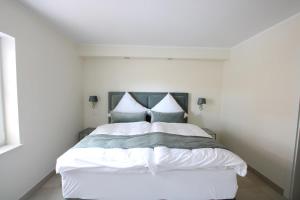 um quarto com uma cama com lençóis brancos e almofadas azuis em Seeblick 1 em Norddeich