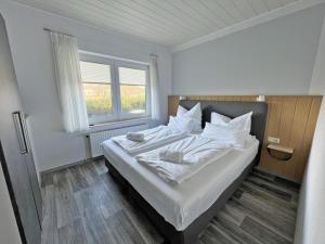 Schlafzimmer mit einem Bett mit weißer Bettwäsche und einem Fenster in der Unterkunft Deichblick 4 in Norddeich- Urlaub und Erholung am Strand in Norden