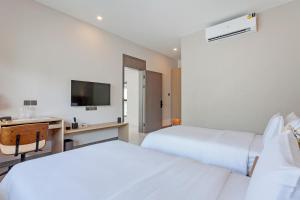 two beds in a room with a desk and a television at 可提供早餐的三卧私家泳池家庭别墅 in Ban Huai Yai