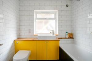 a bathroom with a sink and a toilet and a window at Spacious Stratford house in London