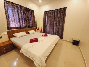 a bedroom with a bed with two red pillows on it at Hotel Mahadev Family Lodging and Boarding in Neral
