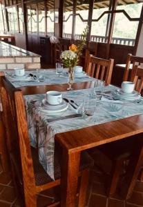 una mesa de madera con platos y vasos. en Vinha dos Lagos Hotel, en Rancho Queimado