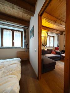 ein Schlafzimmer mit einem Bett und einem Sofa in einem Zimmer in der Unterkunft Hostdomus - Via Roma Suite in Cesana Torinese