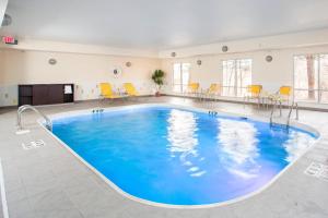 uma grande piscina num quarto com cadeiras amarelas em Fairfield Inn & Suites Ashland em Ashland
