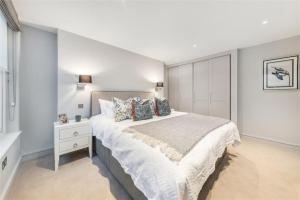 1 dormitorio con 1 cama blanca grande y mesita de noche en Gorgeous Lux Large Belgravia Flat, en Londres
