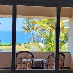 a view of a palm tree from a window at Seashore Beach Resort Varkala in Varkala