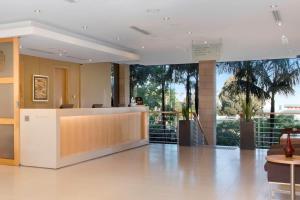 a lobby with a reception desk and palm trees at Courtyard by Marriott Sydney-North Ryde in Sydney