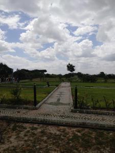 Shelta Village View Resort في Mbuguni: طريق يؤدي إلى حقل مع سماء غائمة