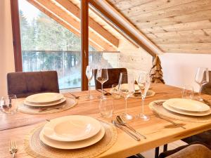 a wooden table with plates and wine glasses on it at Alpen Luxury Lodge, MARIAZELL in Mariazell