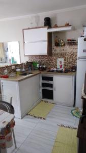 Il comprend une cuisine équipée de comptoirs blancs et d'un réfrigérateur blanc. dans l'établissement Casa do Braga, à Cabo Frio