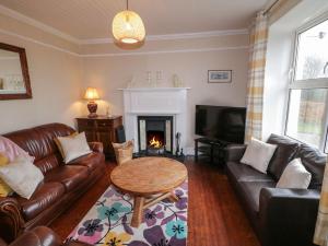 a living room with a couch and a table and a fireplace at Alcorns Farmhouse in Letterkenny