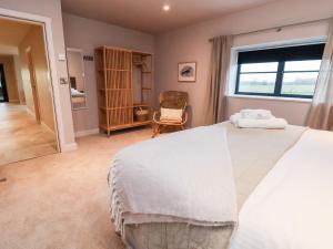 a bedroom with a large white bed and a chair at Grange Barn in Shrewsbury