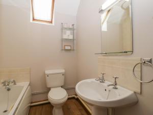 a bathroom with a toilet and a sink and a tub at Anvil Cottage in Blakeney