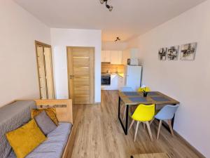 ein Wohnzimmer und eine Küche mit einem Tisch und gelben Stühlen in der Unterkunft Apartmán 4, K Lanovce in Jáchymov