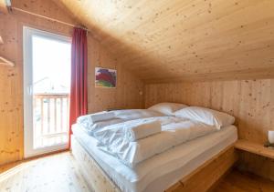 Cama en habitación de madera con ventana en 1A Chalet Nest - Grillen und Wandern, Panorama Sauna!, en Klippitztorl