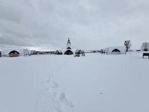 a group of people standing in the snow near tents at Hunnia - Huntanya in Vlăhiţa