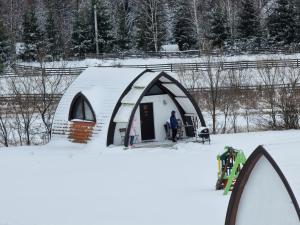 a man standing outside of a tent in the snow at Hunnia - Huntanya in Vlăhiţa