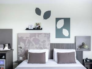 a bedroom with a bed with two pillows at Mercure Compiègne Sud in Compiègne