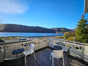 a balcony with chairs and a view of the water at Hôtel La bonne hôtesse in Chambon-sur-Lac