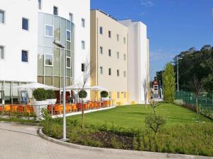 un edificio con sillas naranjas frente a un edificio en Hotel ibis Lisboa Alfragide, en Lisboa