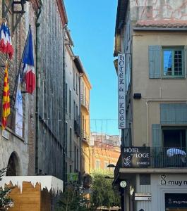 a street in a city with buildings and flags at H&ocirc;tel De La Loge in Perpignan