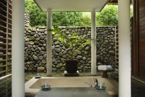 a bathroom with a sink and a stone wall at Alila Ubud in Ubud