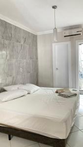 a white bed in a bedroom with a stone wall at Casa de 2 QUARTOS COM PISCINA in Balneário Camboriú