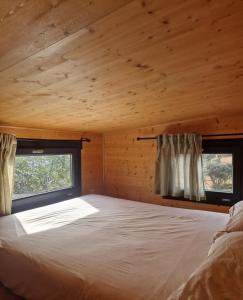 a bedroom in a log cabin with a bed and two windows at Location Tiny House Loule in Loulé