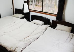 2 Betten in einem Zimmer mit weißer Bettwäsche und Kissen in der Unterkunft Sunland S45 - Vacation STAY 45835v in Saikubo