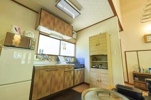 eine Küche mit Holzschränken und einem weißen Kühlschrank in der Unterkunft Sunland S45 - Vacation STAY 45835v in Saikubo