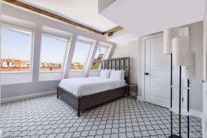 a bedroom with a bed with white sheets and windows at Georgetown Residences by LuxUrban, Trademark Coll by Wyndham in Washington
