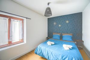 een slaapkamer met een blauw bed en handdoeken bij Le 2en1 Roissy CDG in Longperrier