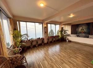 Habitación vacía con ventanas grandes y suelo de madera. en Darjeeling Heights - A Boutique Mountain View Homestay, en Darjeeling