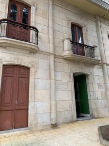 a stone building with two doors and a balcony at MANSIÓN DEL INDIANO in Viveiro