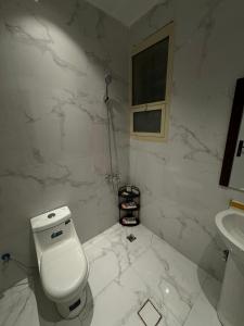 een witte badkamer met een toilet en een wastafel bij Family Modern 2BDR Apartment in Riyad