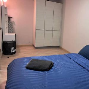 um quarto com uma cama azul com uma toalha preta em 2Bedroom, WiFi, washing machine and small kitchen em Pak Kret