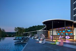 Ein Resort mit einem Pool mit aufblasbaren Stühlen und einem Gebäude in der Unterkunft Aloft Langkawi Pantai Tengah in Pantai Cenang