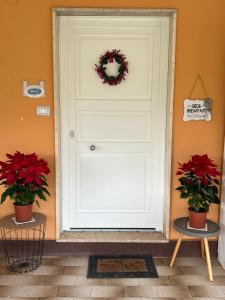 uma porta branca com uma coroa de flores ao lado de duas plantas em The Arches House IUN F1092 em Alghero