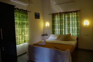 a bedroom with a bed and two windows at Marari Anns Casa Beach Homestay in Mararikulam