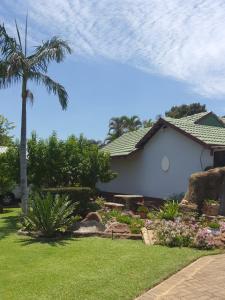 a house with a palm tree and a yard at Jean Michael Self-catering apartment for stay overs in Pretoria
