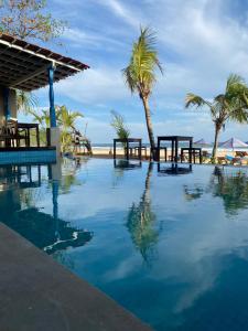 塔拉拉南的住宿－塔拉拉灣海灘酒店，海滩上带桌子和棕榈树的游泳池