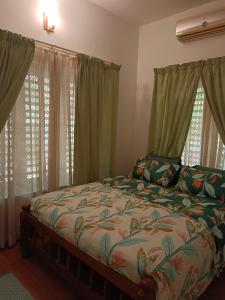 Schlafzimmer mit einem Bett und grünen Vorhängen in der Unterkunft Raaga on the Beach in Kannur