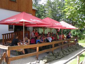 a group of people sitting at a restaurant under red umbrellas at Wellness Hotel Marlin in Nová Pec