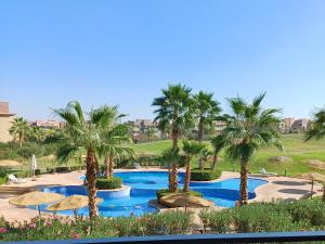 a pool with palm trees and umbrellas in a resort at Prestigia Marrakech Golf 'Dar Cheryana' in Marrakech