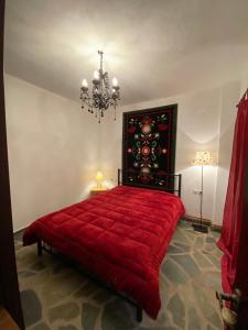 a bedroom with a red bed and a chandelier at La casa Varsani in Anilio