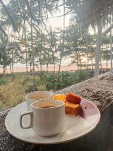 two cups of coffee and a plate of food at Raaga on the Beach in Kannur