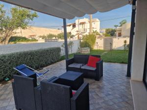 a patio with a couch and chairs under an umbrella at La Palma del Nonno in Mazara del Vallo