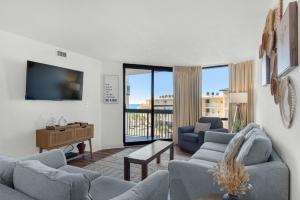 a living room with couches and a flat screen tv at SunDestin 416 in Destin